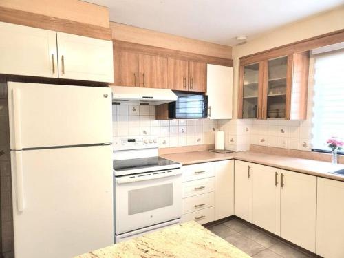 拉瓦尔Comfortable entire 3BDR Apt in Laval Montreal的厨房配有白色家电和木制橱柜