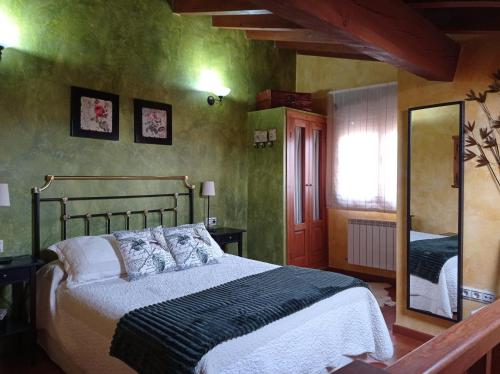 1 dormitorio con 1 cama grande y espejo en casa rural EL RICON, en Navadijos