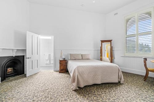 a white bedroom with a bed and a fireplace at Empire Hotel Queenstown in Queenstown