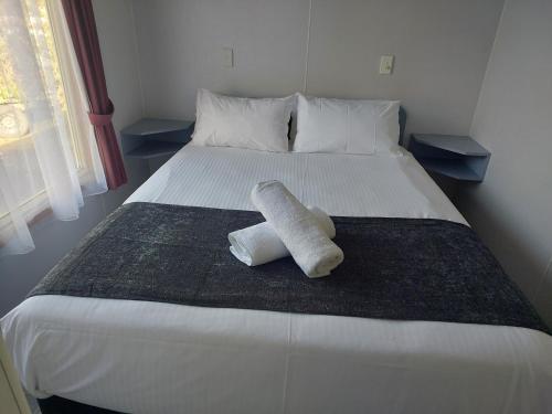 a bed with a towel laying on it at Casuarina Cabins in Nelson