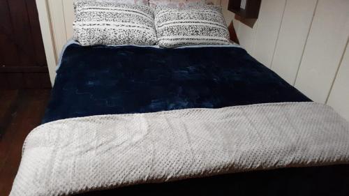 a bed with a blue and white blanket and pillows at Chalé das Margaridas in Rio Forcação
