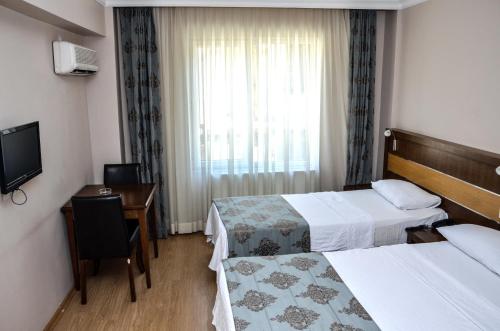 a hotel room with two beds and a desk and a television at Perla Hotel in Dikili