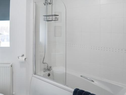 a white bathroom with a shower with a glass door at The Bandstand Sea View in Blythe