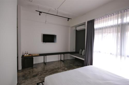 a bedroom with a bed and a tv on the wall at La Pause Hatyai in Hat Yai