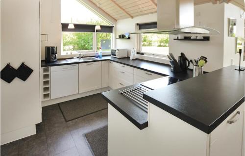 a kitchen with white cabinets and a black counter top at Holiday Home Hyldemose Sydals Iii in Skovby