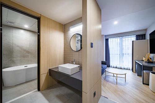 y baño con lavabo, bañera y espejo. en Hound Hotel Hadan, en Busan