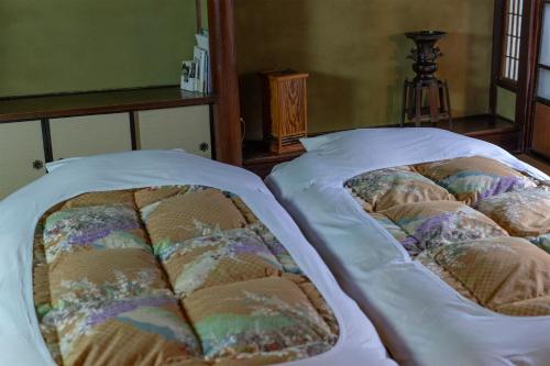 Una cama con sábanas blancas y almohadas. en Itsumoya, en Miyajima
