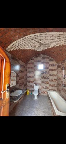 y baño con aseo, bañera y lavamanos. en Nuba life Mostafa Guesthouse en Najâ€˜ al MadÄbb