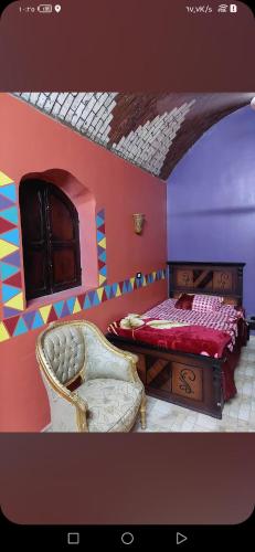 a bedroom with a bed and a chair at Nuba life Mostafa Guesthouse in Najâ€˜ al MadÄbb