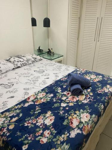 a bed with a blue blanket with flowers on it at Apartment Neo 2.0 in Maceió