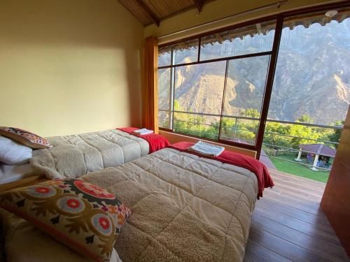 two beds in a room with a large window at Posada Gloria in Tapay