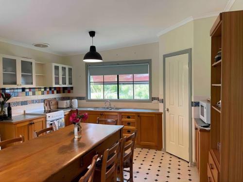 uma cozinha com uma grande mesa de madeira e cadeiras em Relaxing & beautiful Miner's cottage near Wilson’s Prom em Foster