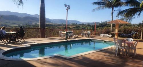 a swimming pool with a table and chairs and people sitting around it at Pousada Vale dos Sonhos - Suite Master com Hidromassagem in Capitólio