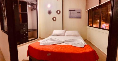 1 dormitorio pequeño con 1 cama con manta roja en Acogedor Estudio 310 Cartagena Bocagrande a 1 cuadra de la playa, en Cartagena de Indias