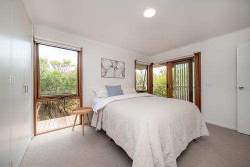 a white bedroom with a bed and a window at TJ's Tree House with Ocean Views in Cape Schanck