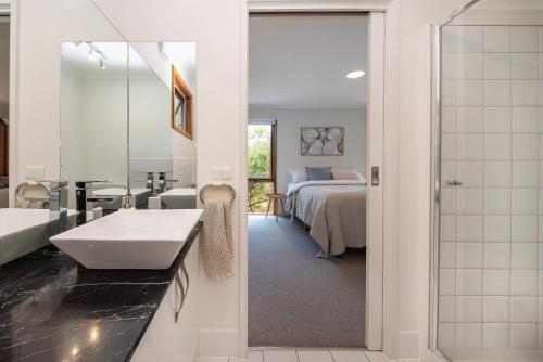 baño con lavabo, cama y espejo en TJ's Tree House with Ocean Views, en Cape Schanck