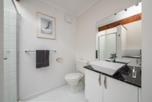 a white bathroom with a toilet and a sink at TJ's Tree House with Ocean Views in Cape Schanck