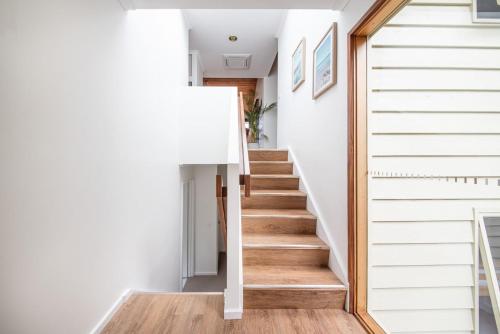 a staircase in a house with white walls and wood floors at TJ's Tree House with Ocean Views in Cape Schanck