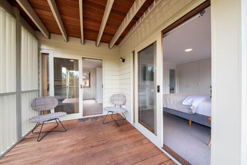 1 dormitorio con 1 cama y 2 sillas en el porche en TJ's Tree House with Ocean Views, en Cape Schanck