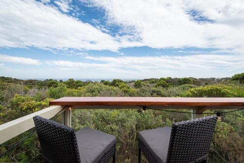 a table and chairs on a balcony with a view at TJ's Tree House with Ocean Views in Cape Schanck