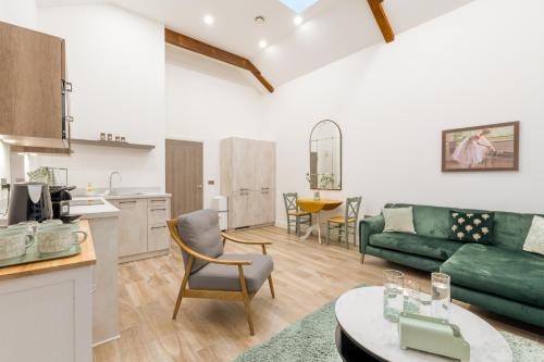 a living room with a green couch and a kitchen at Deansgate Luxury Apartments in Manchester