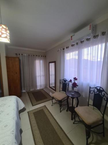 a bedroom with a bed and a table and chairs at Pousada Quinta dos Colibris in São Bento do Sapucaí