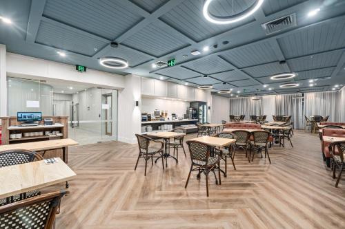 a restaurant with tables and chairs in a room at Mercure Pakenham in Pakenham