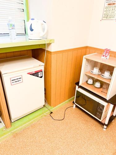a small kitchen with a microwave next to a shelf at ホテル亀岡 in Minamijō