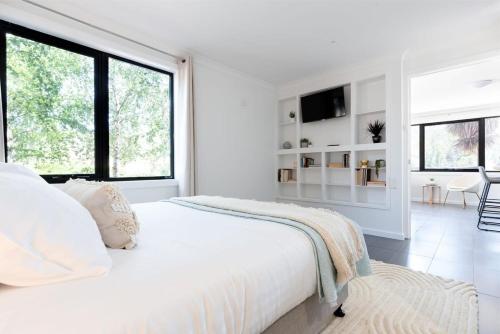 a white bedroom with a large bed and large windows at Hadspen Riverview Retreat: 2 Bedroom Unit in Hadspen