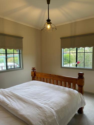 a bedroom with a bed and two windows at Relaxing & beautiful Miner's cottage near Wilson’s Prom in Foster