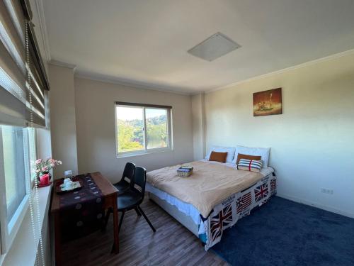 1 dormitorio con cama, escritorio y ventana en Baguio BELL Staycation, en Baguio