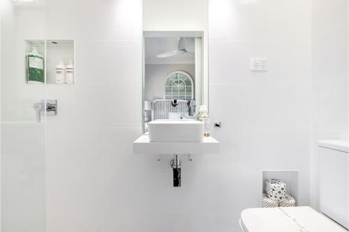een witte badkamer met een wastafel en een spiegel bij Cloud Nine 18 Wynne Crescent in Corlette