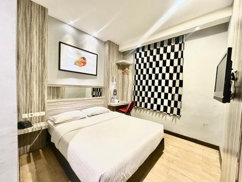 a bedroom with a white bed and a television at My Home Hotel Pontianak in Pontianak