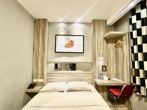 a bedroom with a bed and a table and a window at My Home Hotel Pontianak in Pontianak
