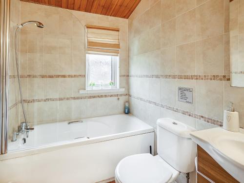 a bathroom with a tub and a toilet and a sink at Cabin Retreat in Skelmorlie