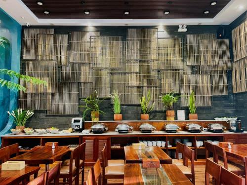 a restaurant with wooden tables and chairs and potted plants at Luu Ngai Condotel Quy Nhon in Quy Nhon