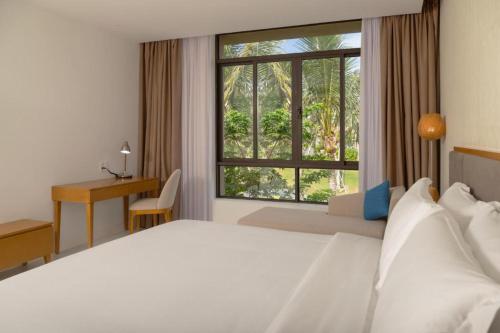 une chambre avec un grand lit blanc et une fenêtre dans l'établissement Apartment in Wyndham Garden Cam Ranh, à Nha Trang