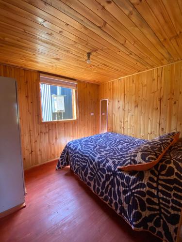 1 dormitorio con 1 cama en una habitación de madera en Rumiloft Cabañas, en Valdivia