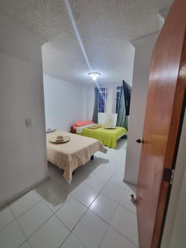 Habitación con 2 camas y mesa. en Apartamento El Rosal, en Ibagué