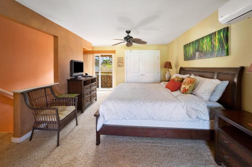 a bedroom with a bed and a chair and a television at Gardenia Suite located across from beach in a boutique property in Kihei