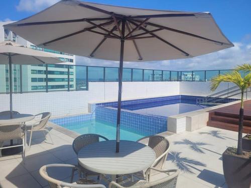 een tafel met een parasol naast een zwembad bij Apartamento Flat em Boa Viagem in Recife