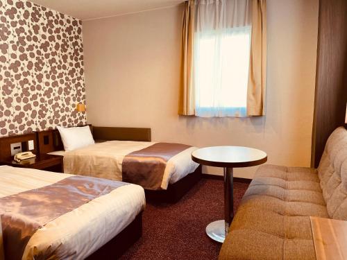 a hotel room with two beds and a couch at Shizuoka Town Hotel in Shizuoka