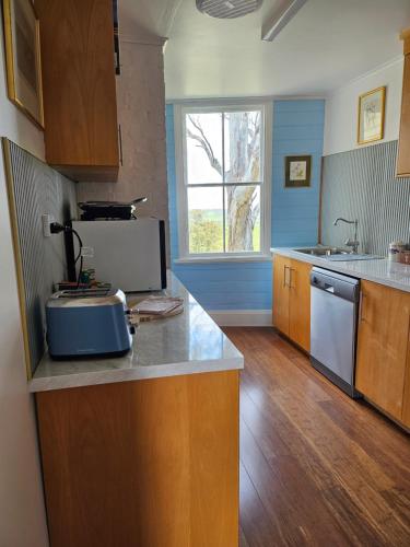a kitchen with a counter with a sink and a window at Stay at Tilba in Central Tilba