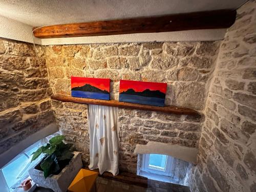 two paintings on a stone wall next to a window at Apartments Trapula in Šibenik