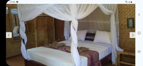 1 dormitorio con cama con dosel y cortinas blancas en Kalinka Inn, en Gili Meno