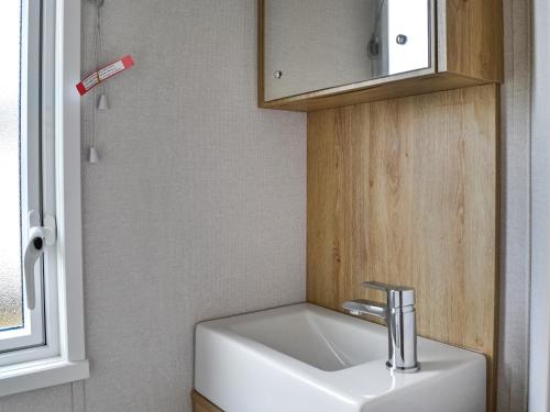 een witte wastafel in een badkamer met een raam bij Paul Jones Bay 63 - Uk46380 in Mainsriddle