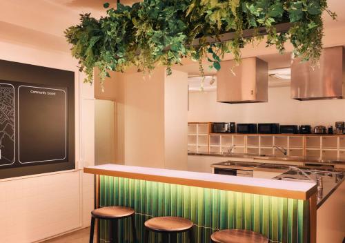 a kitchen with three stools and a counter with plants at Hotel Graphy Nezu in Tokyo