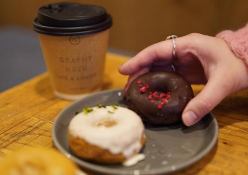 two donuts on a plate next to a cup of coffee at Hotel Graphy Nezu in Tokyo