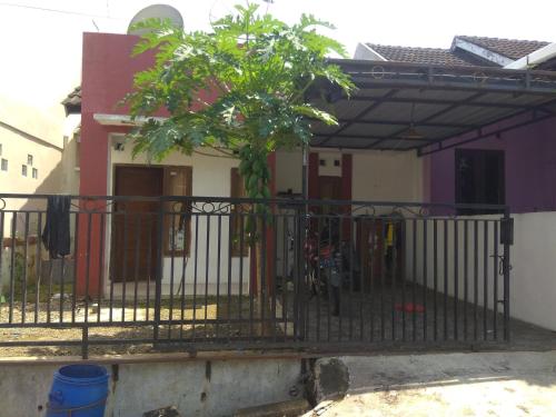 a fence with a tree in front of a house at Guest house TBE C9 in Tambakaji