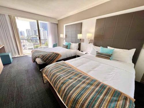ein Hotelzimmer mit 2 Betten und einem großen Fenster in der Unterkunft Sea Views, 150 mtrs to Surfers Beach, Ideal Location for Surfers Paradise in Gold Coast